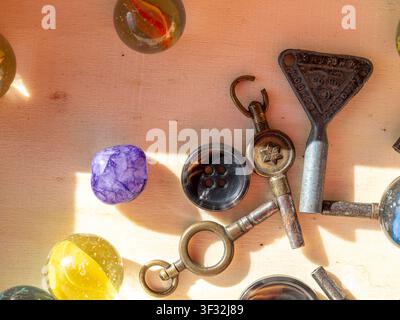 A close-up of a selection of found objects, including clock keys, a button, a marble and purple quartz stone on a wooden background Stock Photo