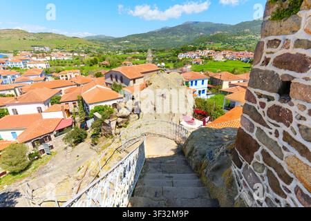 Stone steps lead down from the Panagia Glykofilousa church rock, revealing a picturesque panoramic view of Petra village with its red-roofed houses in Stock Photo