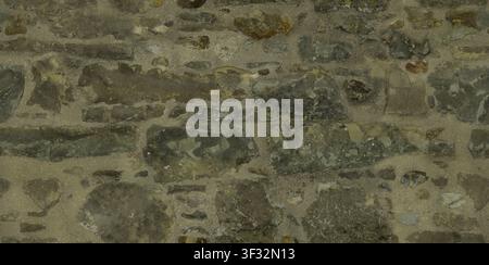 A textured wall surface made of dark irregular stones and thick mortar. Stock Photo