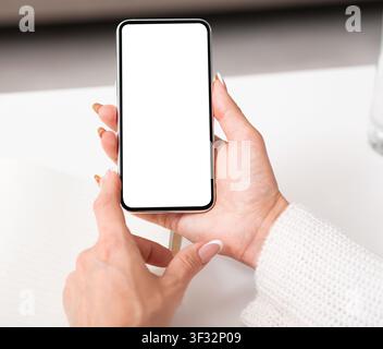 Hands of adult woman are holding smartphone with empty screen Stock Photo