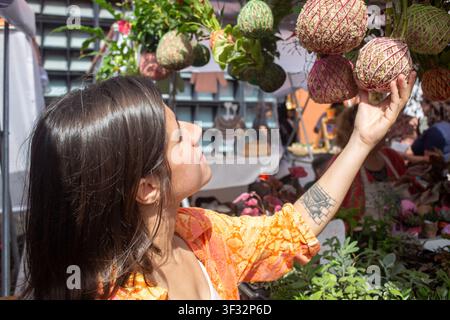 Young woman looking at hanging kokedama plants at an outdoor street market Stock Photo