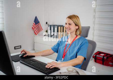 Female healthcare worker smiling while using computer in clinic Stock Photo