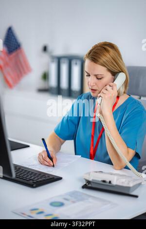 Healthcare professional talking on phone taking notes at desk Stock Photo