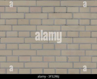 A flat seamless modern beige, cream, and light yellow clay brick wall texture with grey mortar. Stock Photo