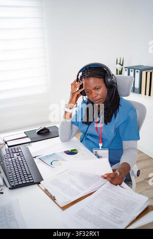 Healthcare worker concentrating on patient data wearing headset Stock Photo