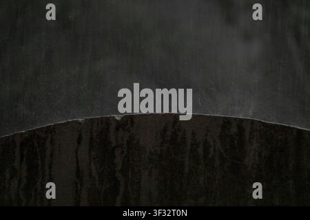 Moody abstract composition featuring water splashing off a weathered charcoal stone ridge. High-contrast, dark atmospheric texture with fluid movement Stock Photo