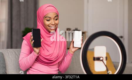 Smiling Young Black Woman Holding Smartphones While Recording Video At Home, Social Media Concept Stock Photo
