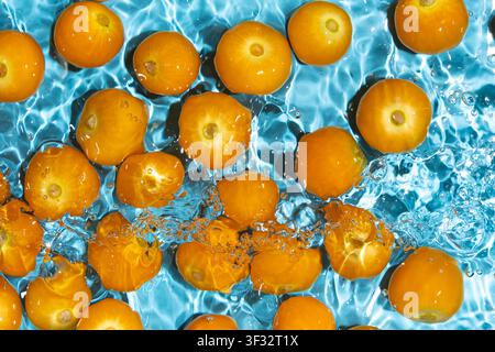 Fresh physalis berries washing in clean water with splashes Stock Photo