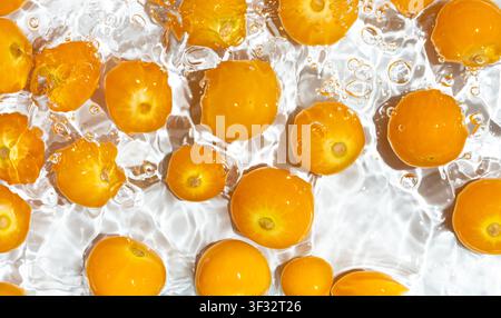 Physalis fruits splashing in water with bubbles top view Stock Photo