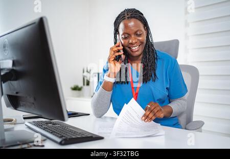 Female nurse communicating on phone while working in office Stock Photo