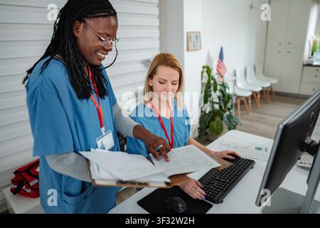 Nurses collaborating in modern clinic office working on computer Stock Photo