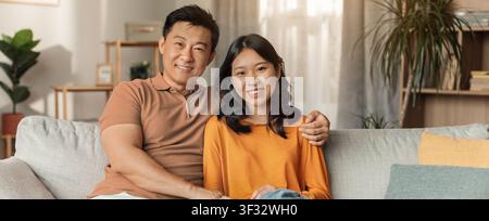 Smiling Asian Man And Woman Relaxing On Couch At Home, Affectionate Togetherness Concept Stock Photo