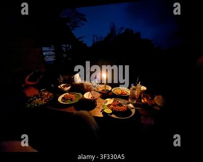 Cozy outdoor dinner with assorted dishes served on a wooden table under the evening sky, creating a warm dining atmosphere. Stock Photo