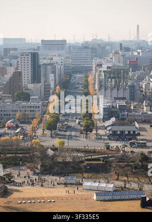 Elevated view looking down a long tree-lined city boulevard stretching toward the distant horizon from Himeji Castle, Japan Stock Photo