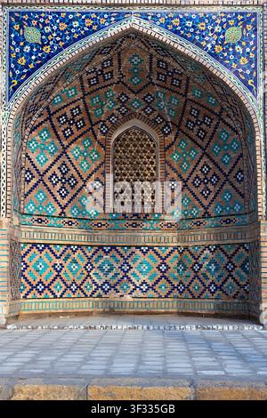 Ornate mosaic tilework niche on Nadir Divan Begi Madrasah in Bukhara, Uzbekistan. Geometric and floral patterns in turquoise and blue decorate the poi Stock Photo