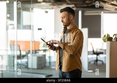 Man Using Tablet In Office, Focused On Digital Device, Business Concept Stock Photo