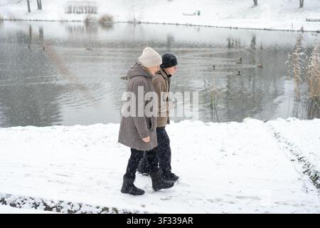 Senior couple walking arm in arm on snowy path. Love knows no age for a loving couple. Tenderness survives cold and affection warms more than clothing. Devoted partners embracing in winter landscape Stock Photo
