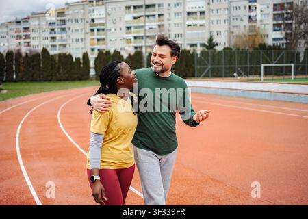 Diverse couple walking together on an urban running track Stock Photo