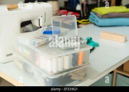 Presser feet organized in a storage container on a table for sewing machine accessory collection. Notions and accessories stored with neat professional care indoors in a home craft room. Stock Photo