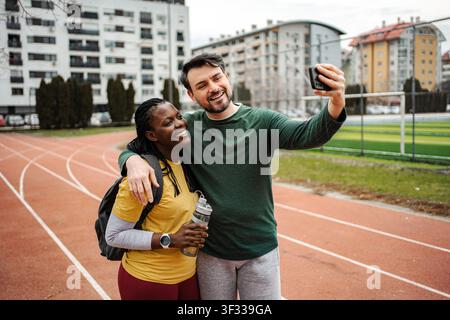 Diverse couple taking selfie at running track after morning workout Stock Photo