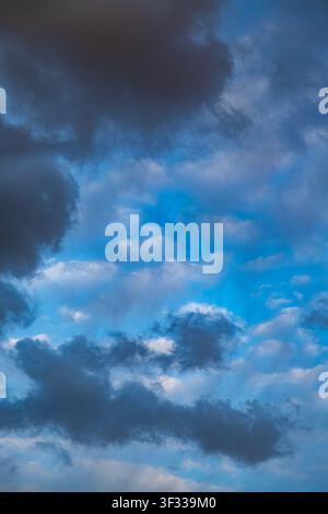Vertical dramatic sky with dark storm clouds framing a bright vivid blue center. Stock Photo