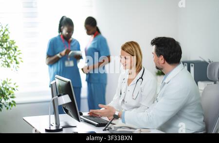 Medical professionals collaborating on computer in modern hospital office Stock Photo