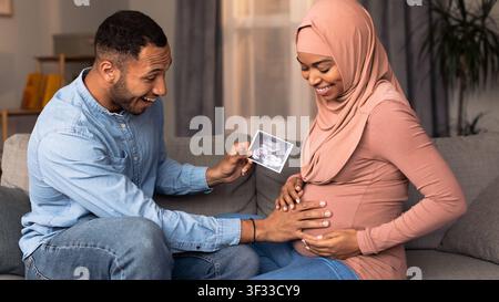 Happy African American Coupleexpecting Baby, Looking At Ultrasound Photo At Home Stock Photo