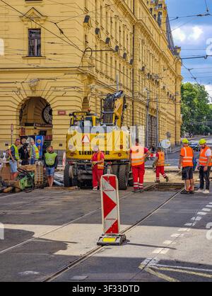 Prague, Czech Republic - July 21, 2026: Construction workers repair tram tracks and the surrounding roadway in the city center using heavy machinery Stock Photo