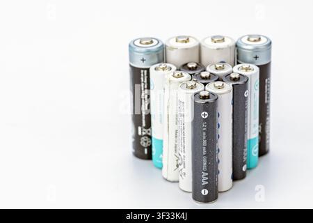 Collection of old used AAA and AA rechargeable batteries standing upright on clean white background Stock Photo