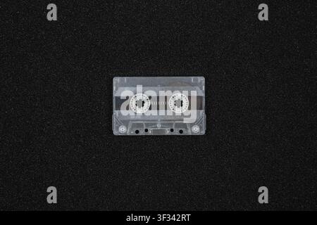 Transparent retro audio cassette tape on black foam rubber background. Stock Photo