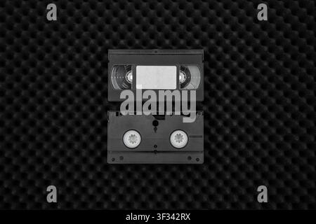 Two black VHS tapes lying on acoustic foam background. Stock Photo