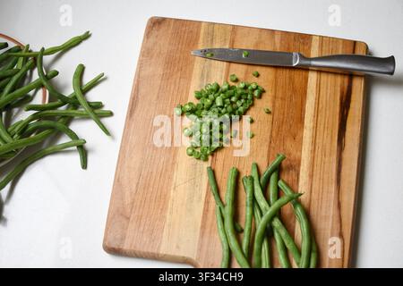 Fresh chopped green beans neatly arranged on a rustic wooden cutting board. Natural texture, vibrant green color, and a healthy organic ingredient Stock Photo