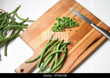 Fresh chopped green beans neatly arranged on a rustic wooden cutting board. Natural texture, vibrant green color, and a healthy organic ingredient Stock Photo