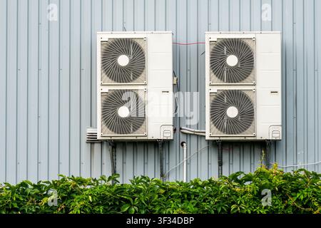 Two outdoor HVAC condenser units installed on a metal building wall, providing efficient cooling and climate control for commercial facilities Stock Photo
