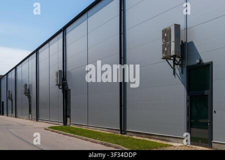Modern warehouse exterior with insulated sandwich panel walls and outdoor HVAC air conditioning units for climate control Stock Photo