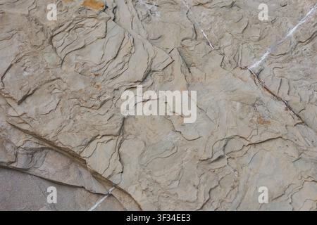 Weathered beige stone surface featuring layered rock formations and natural mineral cracks for earthy abstract backgrounds Stock Photo