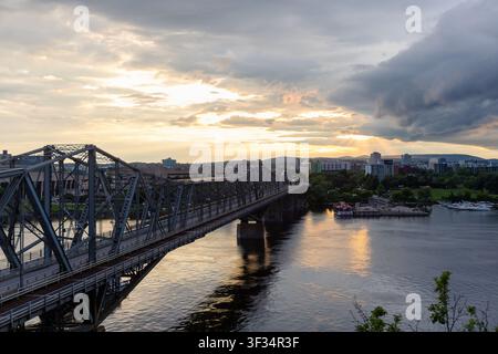 Ottawa, Canada - June 20, 2026: Alexandra Bridge over Ottawa River leading toward Gatineau skyline at dramatic sunset Stock Photo