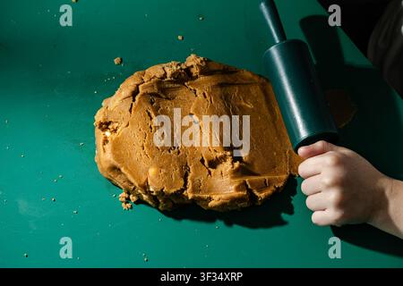 Child Preparing Gingerbread Cookie Dough with Rolling Pin on Green Table Stock Photo