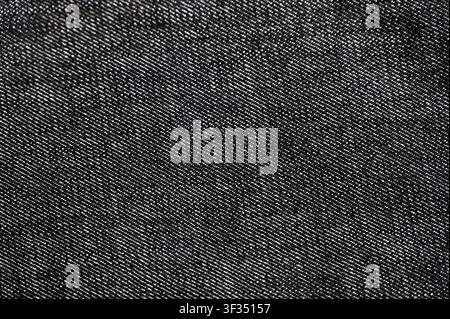 Macro full frame detail of dark grey or black denim textile showing diagonal twill weave pattern. High quality seamless style background concept for fashion, apparel design, casual wear, or background wallpaper. Stock Photo