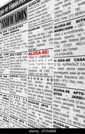 Close-up of fake advertisements with generic information—printed newspaper classifieds offering properties for rent. Text in Brazilian Portuguese. Con Stock Photo