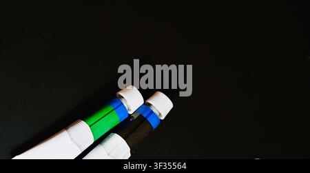 Scattered Colorful Paint Tubes on a Dark Black Background. High quality photoClose-up shot of closed acrylic or oil paint tubes arranged in a scattered fan shape on a solid black background. The dark background creates a strong contrast, highlighting the vibrant colors on the tube labels. Perfect for art supplies concepts, creative studios, painting hobbies, and artistic design backgrounds. Stock Photo