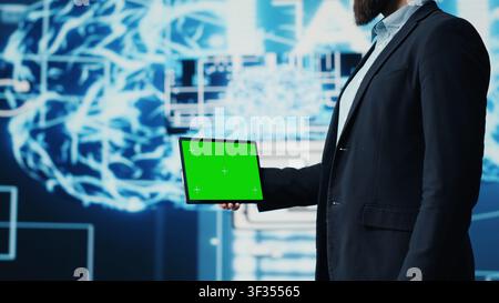 Studying neural networks systems, young IT specialist implements artificial intelligence with mockup screen on tablet. Man using automation for modern AI strategy and innovation. Camera A. Stock Photo