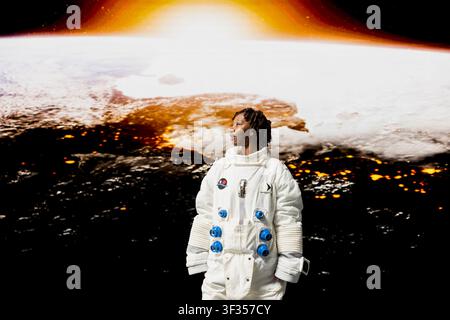 Astronaut wearing space suit in awe while looking at glowing horizon on space shuttle cockpit glass. Woman mesmerized by outer space visuals, concept of planetary discovery and human wonder Stock Photo