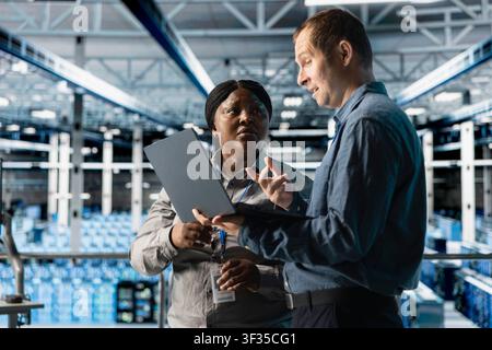 Server farm colleagues upgrading gear for increased processing and storage capacity. Team of data center admins ensuring error free and scalable networks for intense computational demands Stock Photo