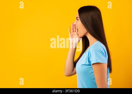 Lady holding palm near mouth, screaming aside at copyspace Stock Photo