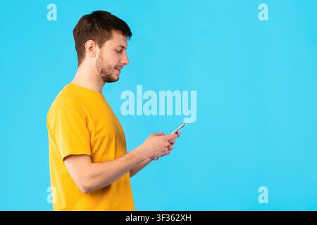 Portrait of young guy using mobile phone, side view Stock Photo