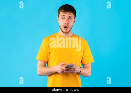 Surprised man using mobile phone at studio Stock Photo