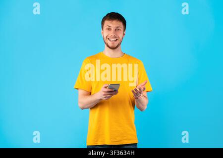 Smiling young man using mobile phone at studio Stock Photo