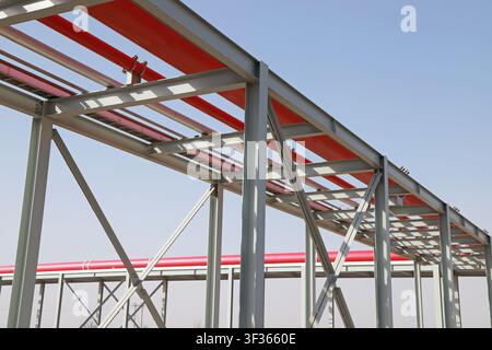 An industrial pipe rack in a factory area, with red pipes neatly arranged on multi-layered steel structure supports, showing the order and power of in Stock Photo