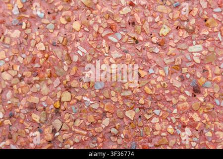 A pink terrazzo floor with small multicolor stone chips creating textured pattern and warm tone, detailed closeup showing aggregate and surface textur Stock Photo